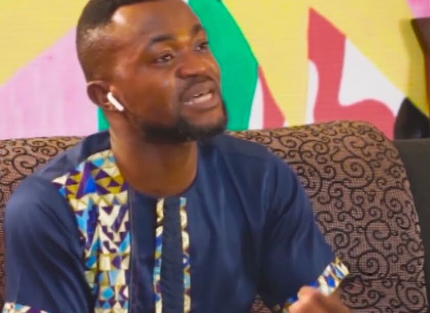 A guest speaking on the Lashone TV studio sofa in front of a colourful backdrop